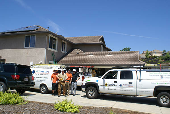 Carnahan Electric/Alternative Electrical Systems Team in front of a neighborhood house with company vehicles